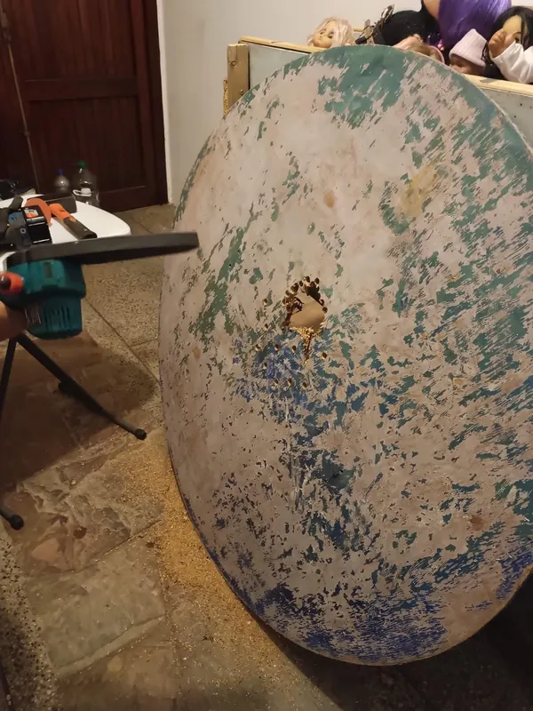 Soporte circular con pintura y huellas de trabajo, apoyado en el taller.