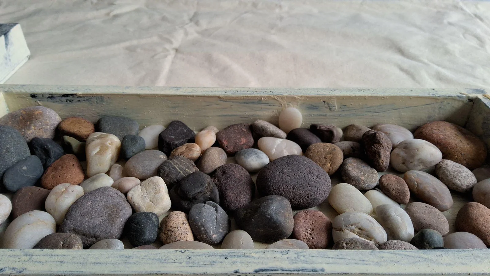 Piedras de distintas formas y colores junto a una tela blanca.